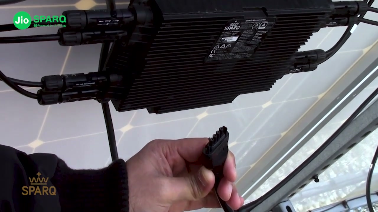 The T5 AC connector in an installer's hand beneath the mounted unit